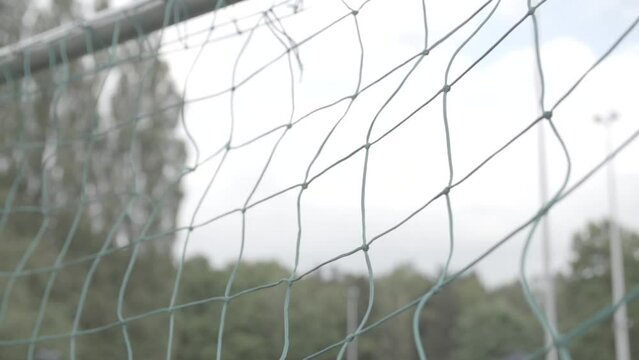 Close up slowmotion shot of a football flying into the green net of a goal on a cloudy day LOG