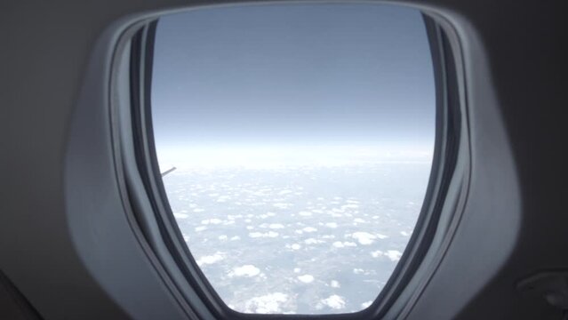 Slowmotion shot filming the wing of a private airplane jet in the sky with a blue sky and clouds in the background LOG