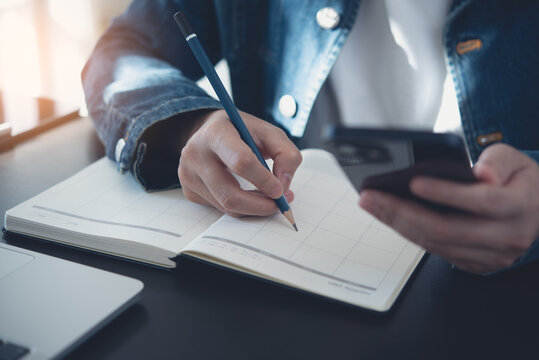 2023 Calendar event planner timetable agenda plan on organize schedule. Business woman using mobile phone with monthly calendar for event planning, Plan scheduling on notebook on office table