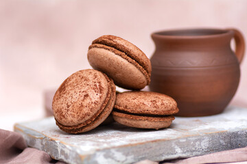 A cup of coffee and chocolate macarons on a wooden board. Breakfast concept.