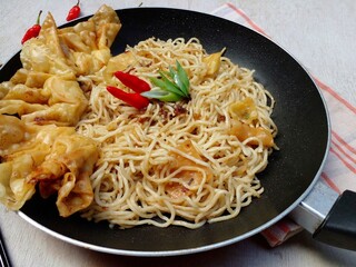 Fried noodles and fried dumplings filled with chopped chicken are placed in a pan. Indonesian Chinese Cuisine.