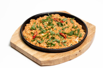 Frying pan with meat in sauce garnished with parsley and hot chili peppers. On a wooden board. Restaurant menu