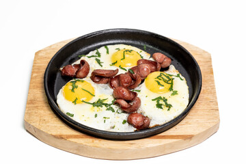 Frying pan with scrambled eggs and fried sausage garnished with parsley. On a wooden board. Isolated on white background. Healthy breakfast concept, restaurant menu