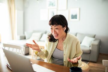 Young Japanese Woman working on a laptop in the kitchen