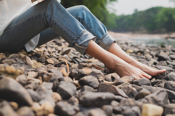 Legs and feet of female is sitting on rocks beside the river. Concept of realxation, meditation, concentration, traveler,  freedom, well being bare foot, recreation, chilling and calming. Enjoy life.