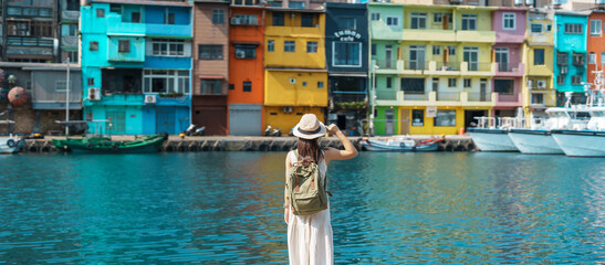 Fototapeta premium woman traveler visiting in Taiwan, Tourist with backpack and hat sightseeing in Keelung, Colorful Zhengbin Fishing Port, landmark and popular attractions near Taipei city . Asia Travel concept