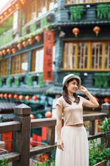 woman traveler visiting in Taiwan, Tourist with hat sightseeing in Jiufen Old Street village with Tea House background. landmark and popular attractions near Taipei city . Travel and Vacation concept