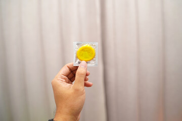 Condom ready to use in man's hand, giving condom concept of safe sex in bed Prevent infection and Contraception control birth rate or safe prophylaxis. World AIDS Day, Leave space for text.