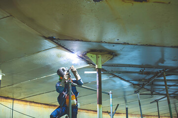 Welding male worker metal arc is part in machinery tank nozzle pipeline construction tank oil inside confined spaces.