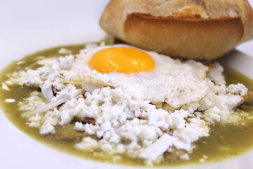 chilaquiles verdes con huevo estrellado. Comida mexicana. Desayuno mexicano. almuerzo mexicano, torilla, masa de maiz, tortilla frita, bolillo, crema y queso