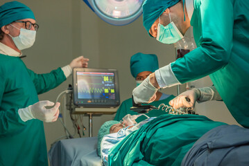 Team of surgery doctor using defibrillator pump chest heart patient to save life while medical surgery in operating room at emergency CPR. Defibrillator in surgeon specialist hand.