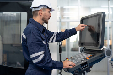 Male engineer operating cnc machine in control panel at factory. Smiling man technician in uniform...