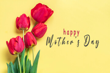 Text Happy Mother's day, red tulips bouquet on yellow backround greeting holiday card Flat lay Top view