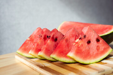 A sliced ripe watermelon is lying on a wooden table
