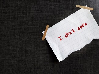 On copy space black background, torn paper with handwritten text I DON'T CARE , to express feeling...