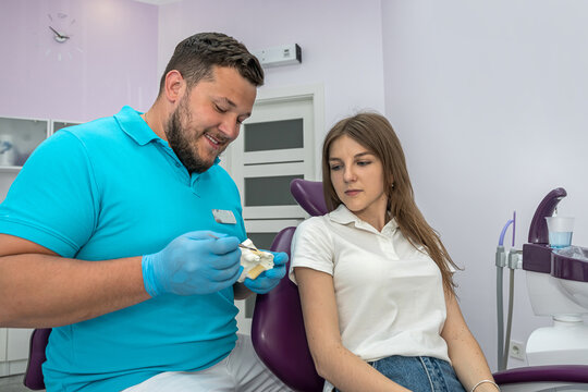 Dentist with hand pointing image and talking to female patient about medication
