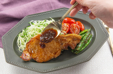 豚ロース肉の生姜焼き風ステーキにソースをかけている瞬間