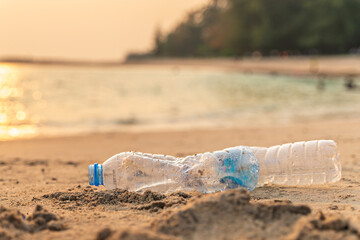 Fototapeta na wymiar Garbage on beach. Empty use dirty plastic bottle and cap. Environmental pollution. Waste Plastic on beautiful sea.