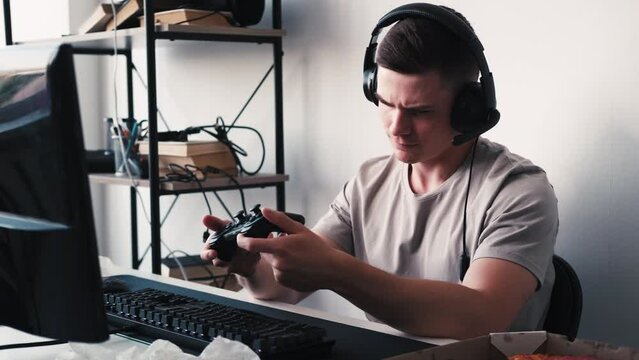 Gaming tools. Exploring console. New joystick. Concentrated man gamer sitting at desk looking at controller seamless loop trying to understand specifics of new gadget. Generative AI