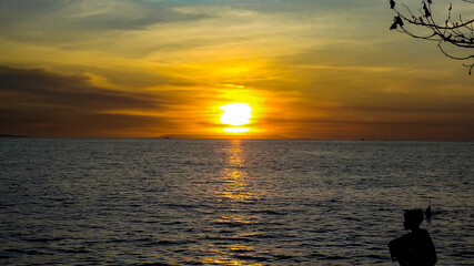 A kid sits on the beach during sunset in in Lombok Island, Indonesia