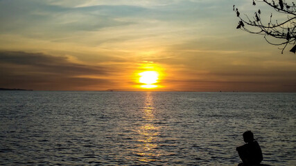 A kid sits on the beach during sunset in Lombok Island, Indonesia