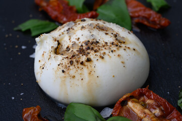 Burrata, an Italian Cow Milk Cheese made from Mozzarella, Stracciatella and Cream from Puglia, Italy, served with Salt, Pepper, Sun dried Tomatoes and Basil