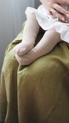 A mother holds a small child in socks in her arms.