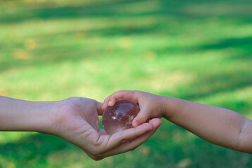 Adult person passes crystal ball to baby hand a healthy ecology to a new generation. Healthy...