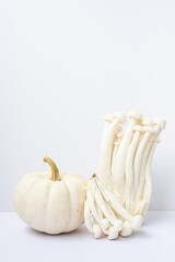 Monochromatic still life of vegetables. Little pumpkin and beech mushrooms on white.