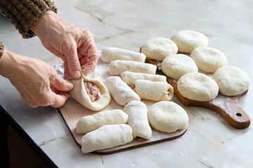 Cooking meat pies at home in the kitchen. An elderly woman prepares pies.