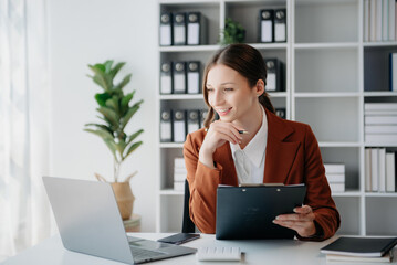 Confident business expert attractive smiling young woman typing laptop ang holding digital tablet...