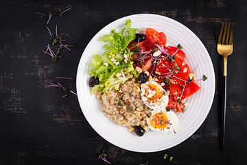 Breakfast oatmeal porridge with boiled egg, cherry tomatoes, olives, nuts and microgreens. Healthy balanced food. Top view, overhead