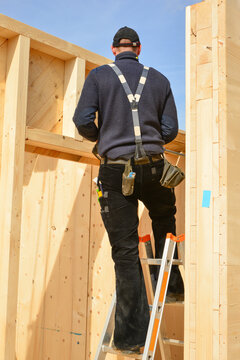 Zimmermann in typischer Arbeitskleidung beim Aufstellen eines Vollholz-Elementhauses