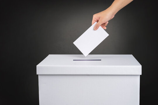 The voter holds his vote ballot paper and places it in the ballot box. Election concept.