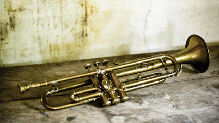 Fototapeta na wymiar an antique Jazz trumpet on an old background of an old house