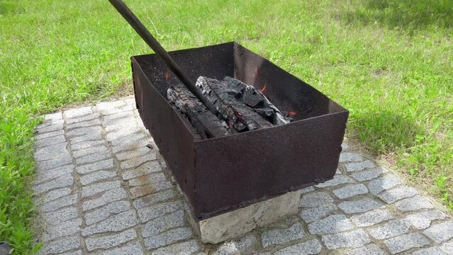 Raking coals in small brazier filled with burning wood. Cooking on the grill. Meat coocking at backyard. firewood. Flames in brazier