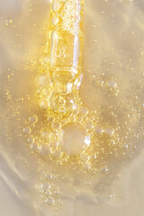 Close up of dropper pipette with yellow liquid on beige backgrund with jelly smear with bubbles of product. Cosmetic,medicine, labaratory test and pharmacy concept.