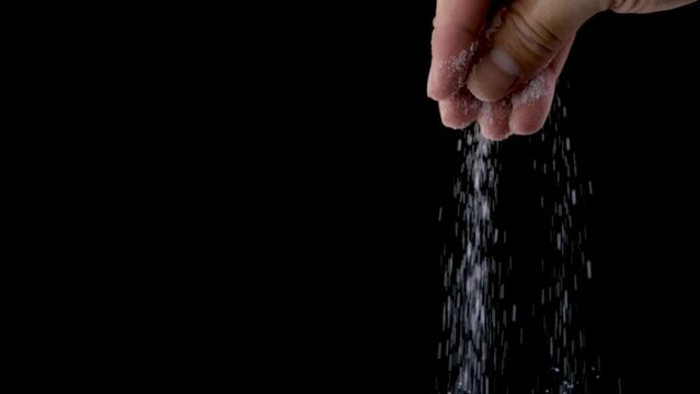 Man's hands are sprinkling salt on food on a black background	