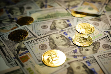 Gold Bitcoin on hundred dollars bills. Close-up