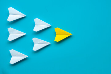 Top view of paper airplane - Yellow paper airplane origami leading other white airplane on blue background.