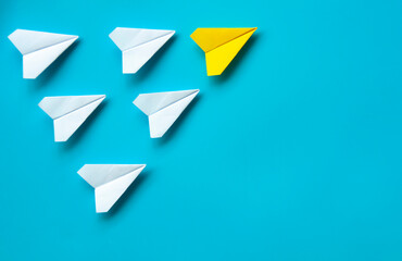 Top view of paper airplane - Yellow paper airplane origami leading other white airplane on blue...