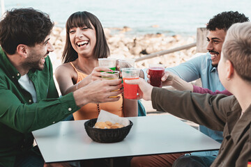 Friends Toasting Seaside - Five friends toasting with colorful fizzy drinks on a seaside terrace during a summer gathering.
