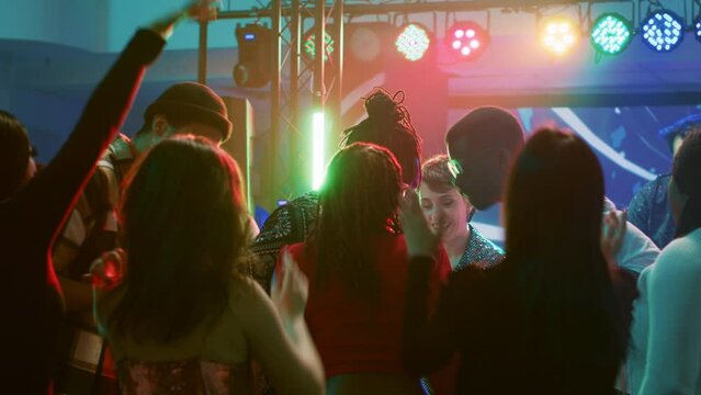 Young adults doing cool dance moves at club, partying together and having fun on electronic music. Diverse crowd of people enjoying night out with live performance on dance floor. Generative AI