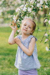 Child girl holds a branch in a blooming spring garden