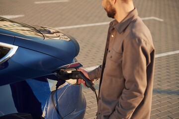 Obraz premium Conception of green energy. Man is standing near his electric car outdoors