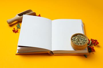 Alternative medicine: blank book and ingredients on yellow background