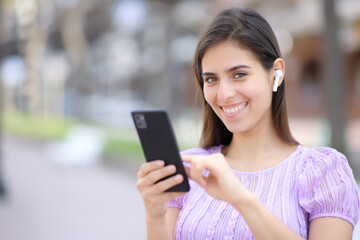 Happy woman posing with earbud and phone