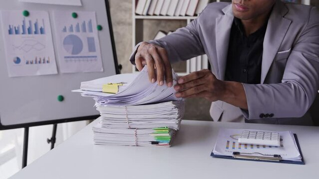 work from office A businessman works a bunch of paper files to find information on his desk at home. business report pile of unfinished documents