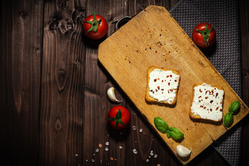 Breakfast photo of cream cheese and bread sliced. Tomato on wooden background.