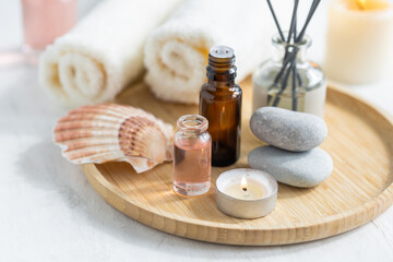 Concept of spa treatment in salon. Natural organic oil, towel, candles as decor. Atmosphere of relax, serenity and pleasure. Anti-stress and detox procedure. Luxury lifestyle. White wooden background